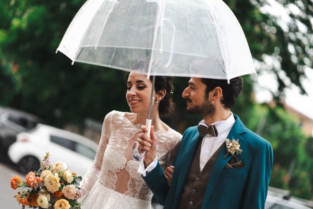 abito da sposa su misura. sposi sotto la pioggia con ombrello