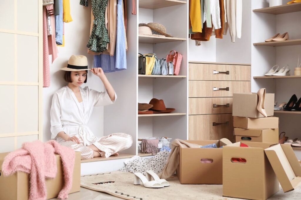 una ragazza un po' demoralizzata durante il decluttering dell'armadio